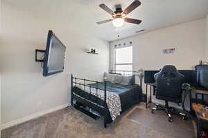 Bedroom with carpet, a textured ceiling, ceiling fan, and a desk