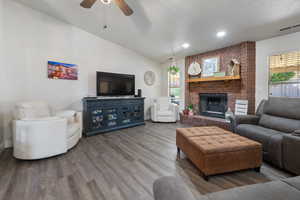 Living area with lofted ceiling, a brick fireplace, wood finished floors, and recessed lighting