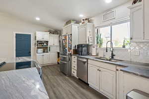 Kitchen with dark stone countertops, tasteful backsplash, stainless steel appliances, dark wood-type flooring, and recessed lighting