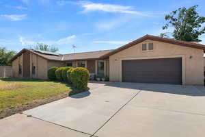Single story home featuring a tiled roof, a front lawn, stucco siding, concrete driveway, and a garage
