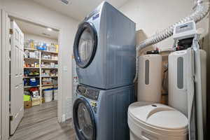 Laundry room with stacked washer and clothes dryer and dark wood finished floors
