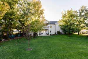 View of grassy yard featuring a patio and a balcony