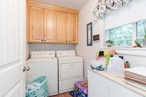 Washroom featuring cabinet space and washing machine and dryer