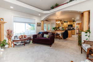 Living room featuring recessed lighting, a chandelier, light colored carpet, arched walkways, and light tile patterned floors