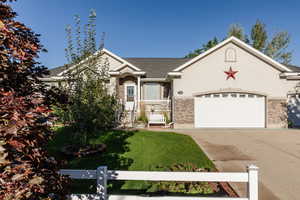View of front of house with a garage, concrete driveway, and stone siding