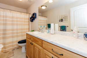 Full bath featuring vanity, a textured ceiling, light tile patterned floors, and a shower with shower curtain