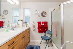 Full bath with a stall shower, vanity, and light tile patterned flooring