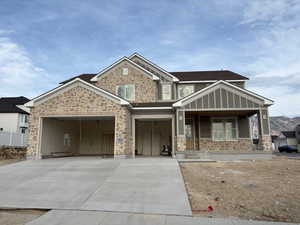 View of front of property featuring a porch, stone siding, concrete driveway, and an attached garage