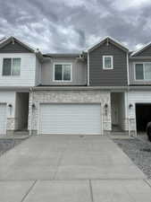 View of front facade with stone siding, concrete driveway, and an attached garage