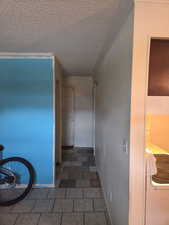 Hallway featuring a textured ceiling, washer / clothes dryer, and tile patterned flooring