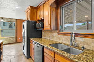 Kitchen featuring plenty of natural light, dark stone countertops, brown cabinets, and a textured ceiling