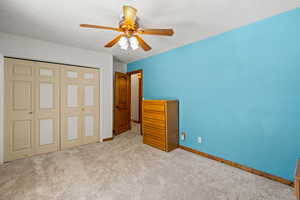 Unfurnished bedroom with a closet, a textured ceiling, carpet flooring, and ceiling fan