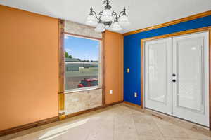 Foyer with a chandelier, french doors, a textured ceiling, tile patterned flooring, and crown molding