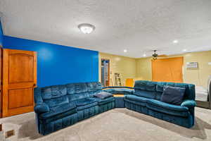 Carpeted living area featuring a textured ceiling, a ceiling fan, recessed lighting, and a wall mounted AC