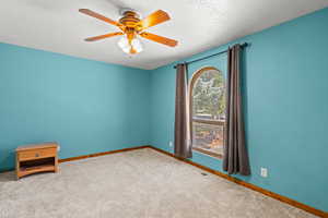 Carpeted empty room featuring a textured ceiling and a ceiling fan