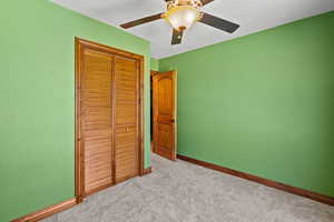 Carpeted bedroom with a textured ceiling, a closet, and ceiling fan