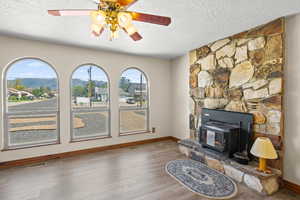 Living area featuring wood finished floors, a textured ceiling, a mountain view, and a ceiling fan
