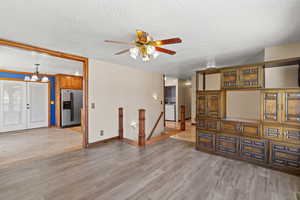 Living room with a textured ceiling, light wood-type flooring, and ceiling fan