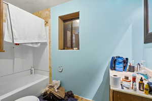 Bathroom with bathtub / shower combination, a textured wall, and a textured ceiling