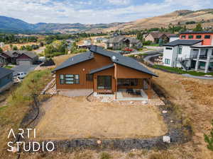 Back of house featuring a mountain view, a residential view, a patio, and board and batten siding