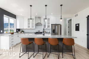 Kitchen featuring glass insert cabinets, a kitchen bar, light stone counters, stainless steel appliances, and hanging light fixtures