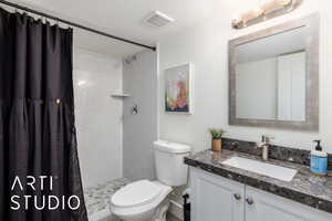 Full bath featuring a textured ceiling, vanity, and a stall shower
