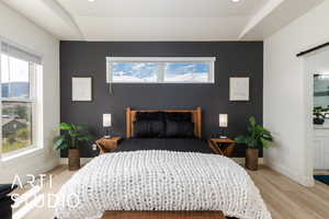 Primary Bedroom featuring light wood-style floors, an accent wall, a barn door, recessed lighting, and multiple windows