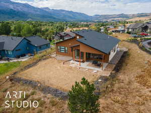 Rear view of property featuring a patio, a mountain view, a residential view, and board and batten siding
