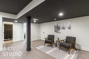 Living area with light wood-type flooring and recessed lighting