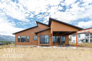 Rear view of property featuring board and batten siding, a patio, and a mountain view
