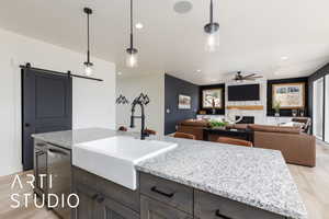 Kitchen with light wood finished floors, pendant lighting, a barn door, light stone countertops, and recessed lighting