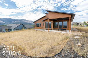 Rear view of house with a mountain view, a patio, and board and batten siding