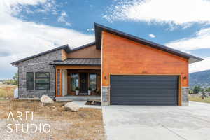 Contemporary house featuring a porch, a garage, stone siding, and a metal roof
