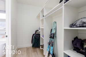 Primary walk-in closet with light wood-type flooring