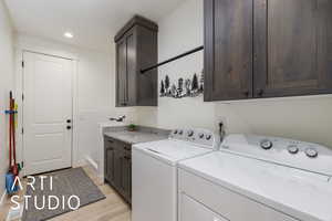 Laundry area featuring cabinet space, washer and clothes dryer, recessed lighting, wainscoting, and light wood-style floors