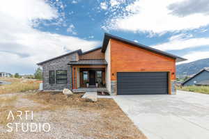 Contemporary home with a standing seam roof, a metal roof, stone siding, and a garage
