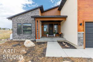 Entrance to property with stone siding, covered porch, and stucco siding