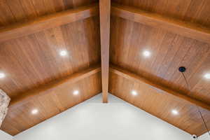 Detailed view of a wooden ceiling with exposed beams, recessed lighting, and a sauna