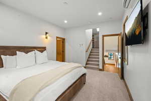 Carpeted bedroom with recessed lighting and a wall mounted AC