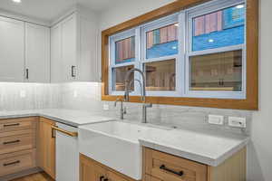 Kitchen with decorative backsplash, light stone counters, and dishwasher