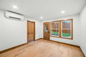 Doorway to outside featuring wood finished floors, a wall unit AC, and recessed lighting