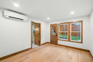 Entrance foyer featuring light wood finished floors, a wall unit AC, and recessed lighting