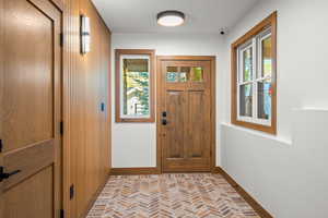 Entryway with brick flooring and baseboards