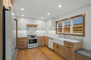 Kitchen featuring backsplash, white appliances, recessed lighting, light wood-type flooring, and light stone countertops