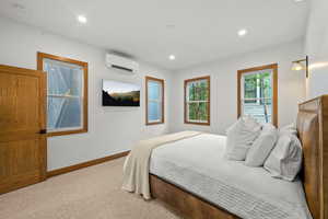 Carpeted bedroom with recessed lighting and an AC wall unit