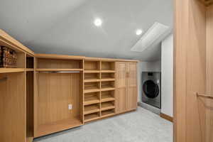 Spacious closet featuring washer / dryer, vaulted ceiling, light colored carpet, and a skylight