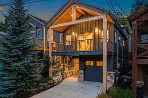 View of front of house with board and batten siding, concrete driveway, an attached garage, stone siding, and covered porch