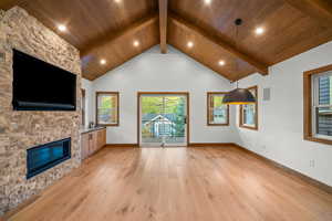 Unfurnished living room with light wood-type flooring, high vaulted ceiling, a fireplace, a wooden ceiling with exposed beams, and recessed lighting