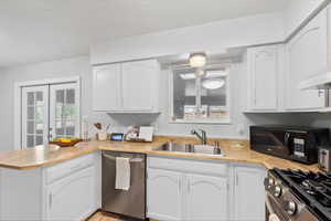 Kitchen featuring a peninsula, white cabinets, appliances with stainless steel finishes, and french doors