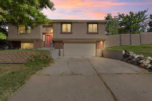 Split foyer home featuring brick siding, driveway, stucco siding, and a garage